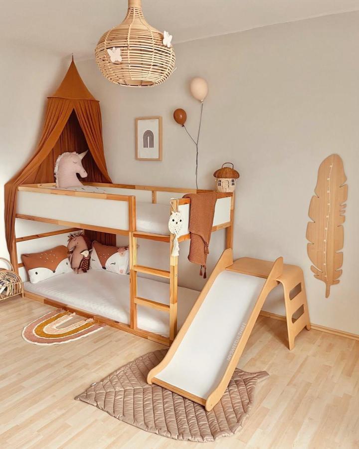 Natural wood Ikea kura bed ideas for small rooms by @my.sweet.lil.three with slide and terracotta canopy in cozy kids’ room.