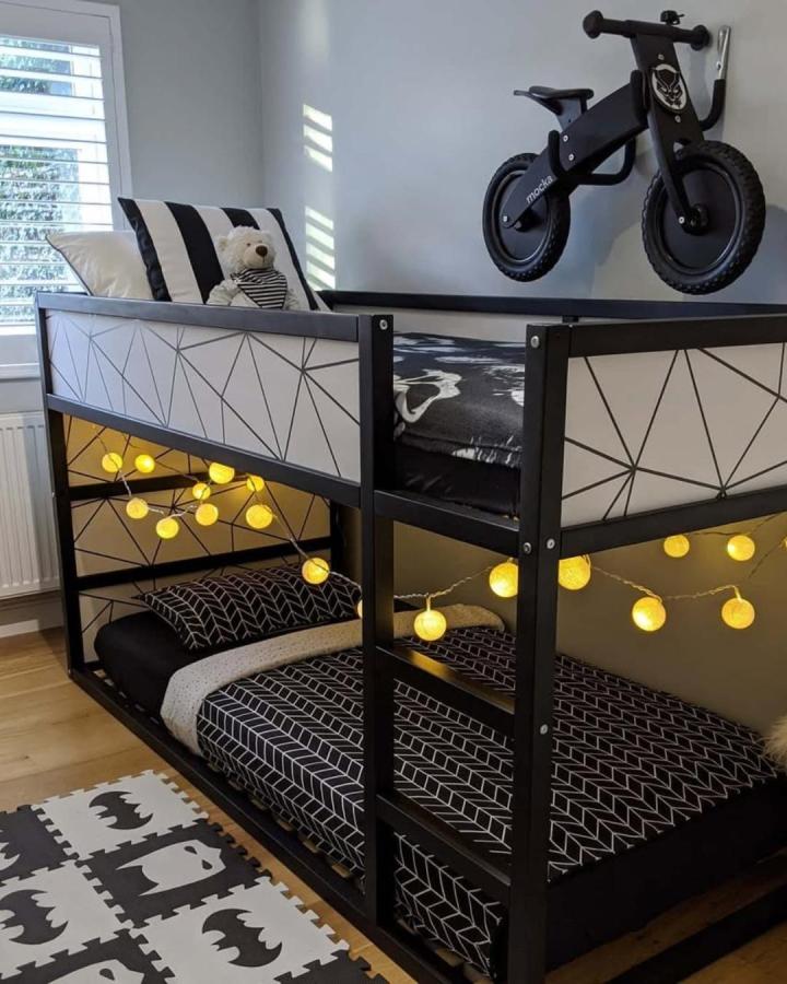 Black and white geometric bunk bed with string lights from @sukicreates. Modern ikea kura bed ideas for small rooms with cozy lighting.