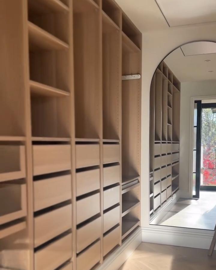 Light wood Ikea pax hacks for walk-in closets with drawers and open shelves reflected in a tall arched mirror from @wonderanddwell.