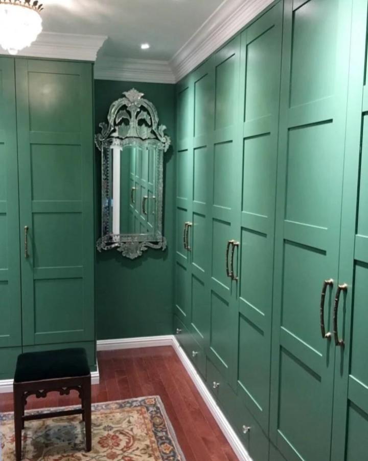 Emerald green paneled Ikea Pax wardrobe doors in walk-in closet from Nini Murphy with bronze handles and vintage mirror.