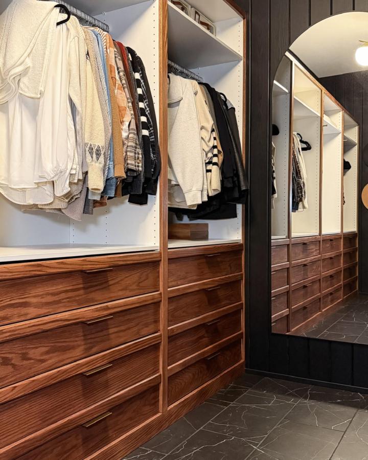 Dark stained wood drawer fronts on white Ikea PAX units in walk-in closet from Simply Aligned Home. Mirror reflects closet storage and tile flooring.