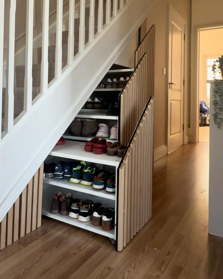 White wooden slat rolling shoe storage under stairs from @mamamikolaja_ in an awkward alcove.
