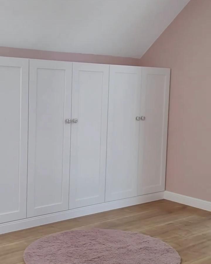 White shaker-style ikea platsa cabinets in sloped alcove room from @domowo.zakrecona. Stylish fitted storage with soft pink walls.