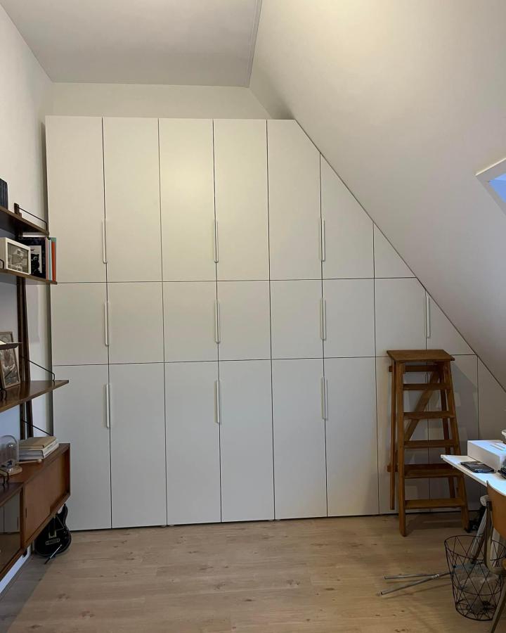 white minimalist modular ikea platsa cabinets in sloped ceiling bedroom by Monique Bultena-Goettsch with wooden ladder and light wood floor