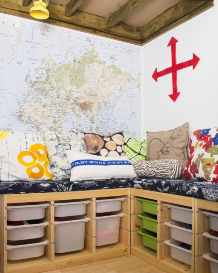 Natural pine wood corner bench with white and green ikea trofast playroom ideas storage bins from put up your dukes bright cushions and world map wall decoration.