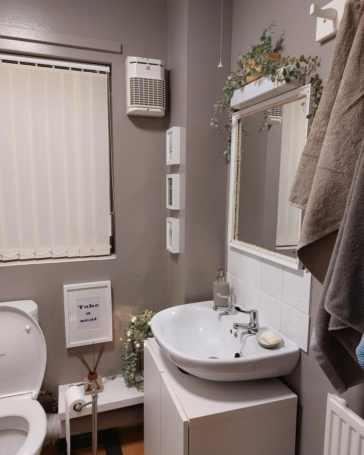 White minimalist bathroom vanity with BESTร
cupboard as base by Minna Jokio featuring taupe walls, mirror, and greenery accents. ikea besta bathroom vanity ideas