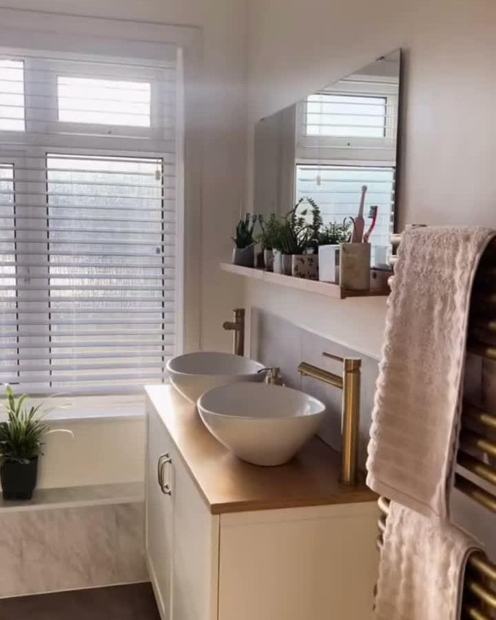 White vessel sinks on wood top Ikea besta bathroom vanity ideas from @lifeathome.x with brass faucets and plants above.