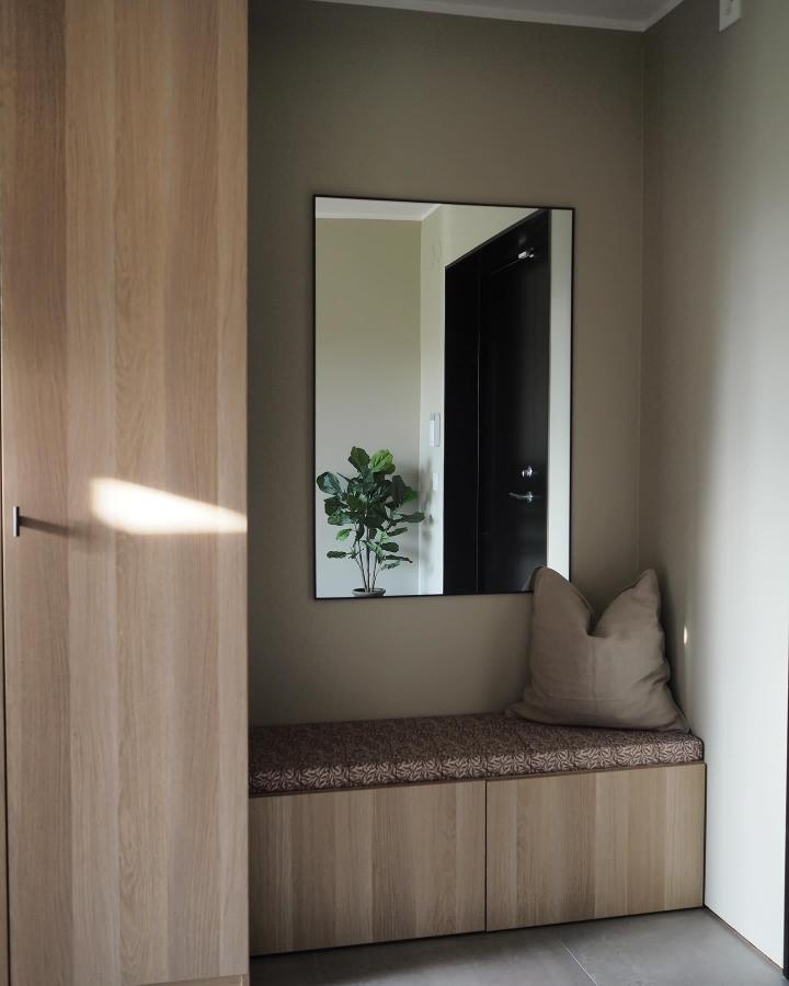 Light wood Ikea besta bench hack seating nook with patterned cushion and pillow by @rebeckakarrbring in a minimalist corner with mirror reflecting plant.