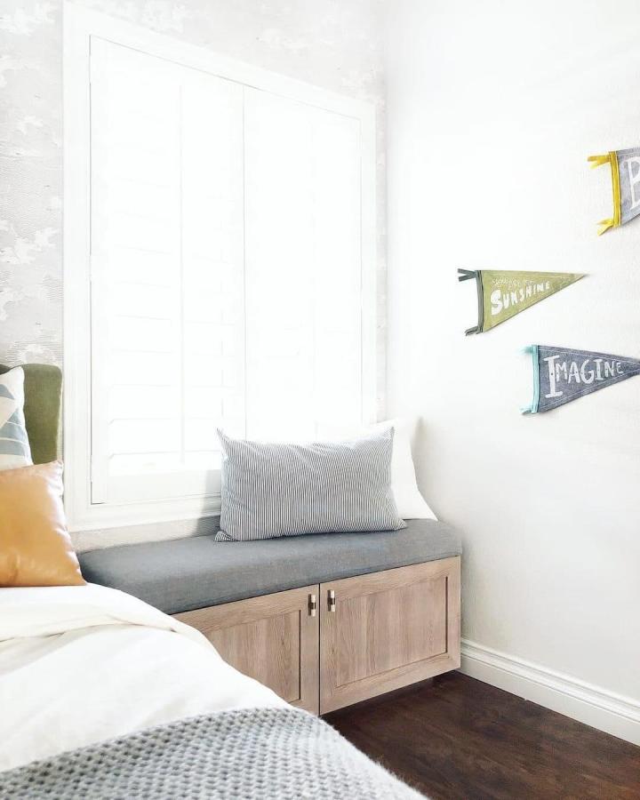 Light wood door ikea besta bench hack with grey cushioned seat and storage beneath in a bright bedroom corner by @chrislovesjulia. Cozy functional seating area.