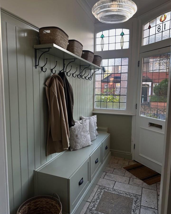 muted green ikea besta bench hack with cushions and black handles in cozy entryway by @thelittlehouseinlondon featuring woven baskets and iron hooks
