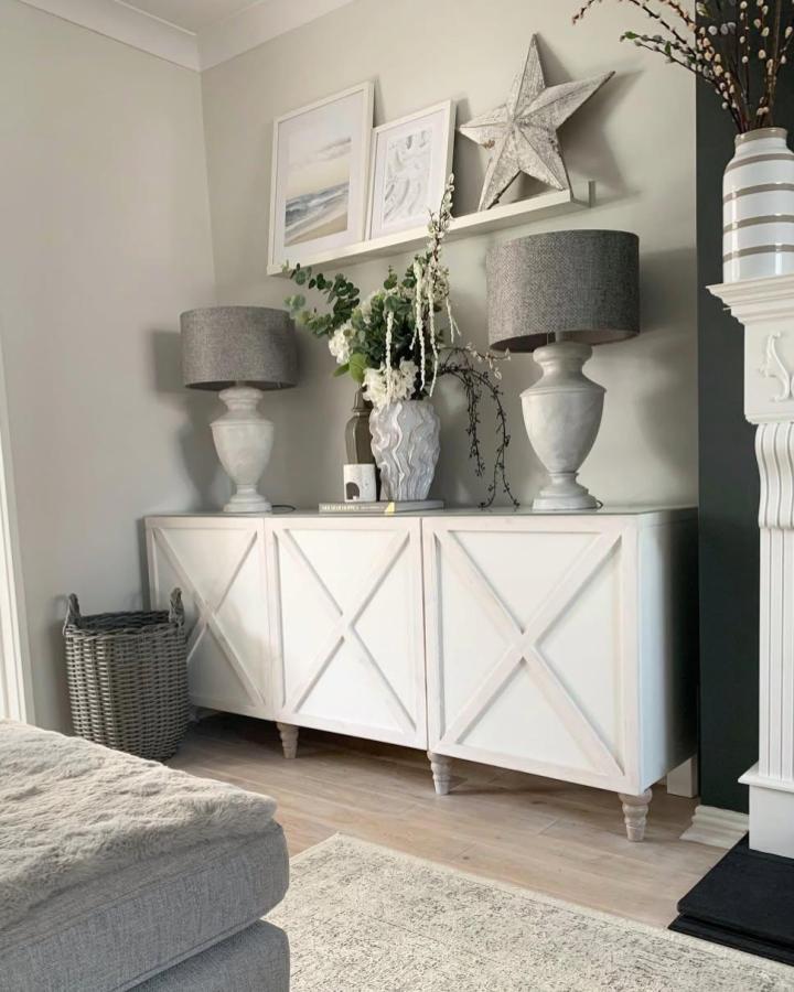 White painted ikea besta sideboard hacks with crisscross panels and turned legs in cozy living room by @dreah.home. Rustic farmhouse style.