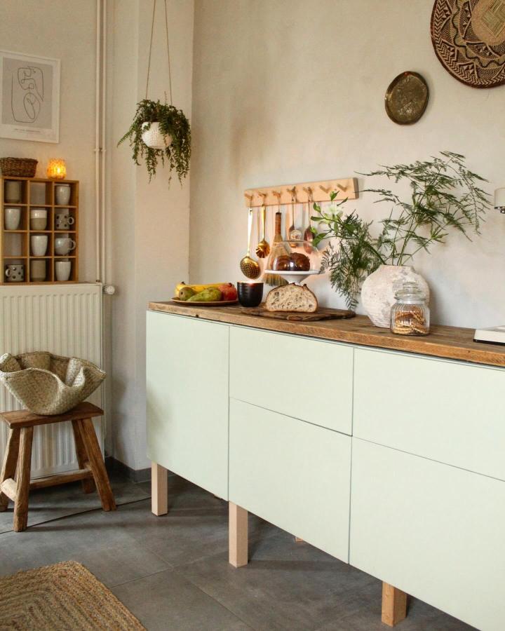 Soft green Ikea Besta sideboard hacks with natural wood legs and countertop in a cozy kitchen setting by @snyggehygge. Minimalist and warm.
