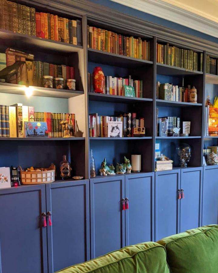 Blue painted Ikea Billy library wall hacks with classic books and decorative tassel pulls in a cozy living room from @s.e.w.athome creating a moody, chic library space