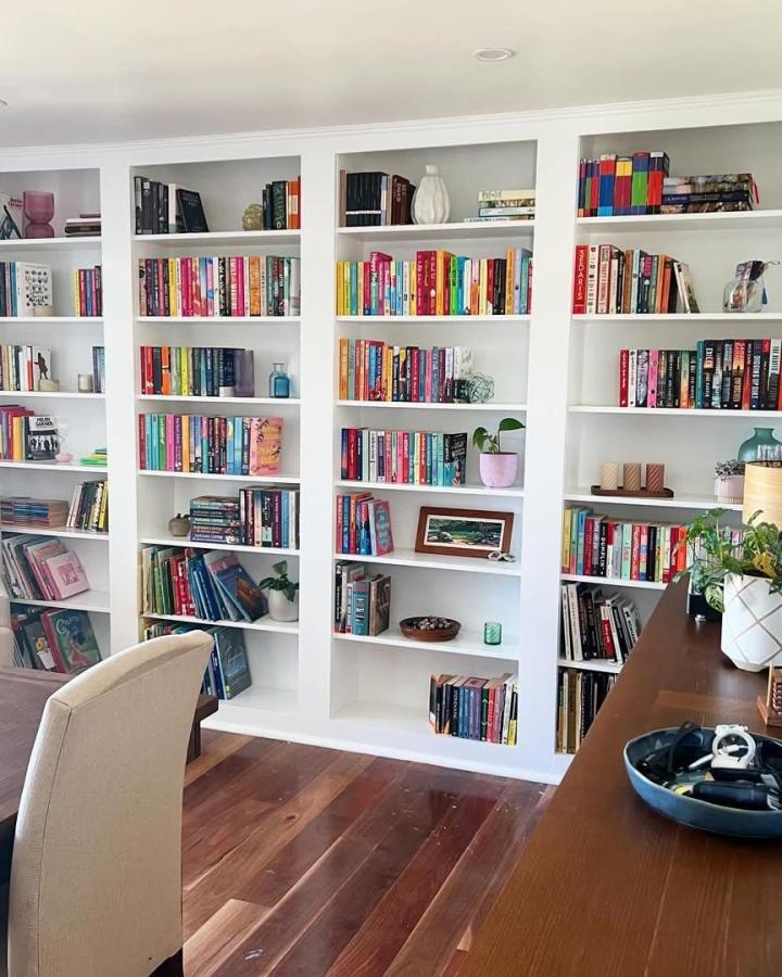 White built-in style ikea billy library wall hacks with colorful books and plants in a cozy living space by @bibliobliss.au. Seamless custom shelves.