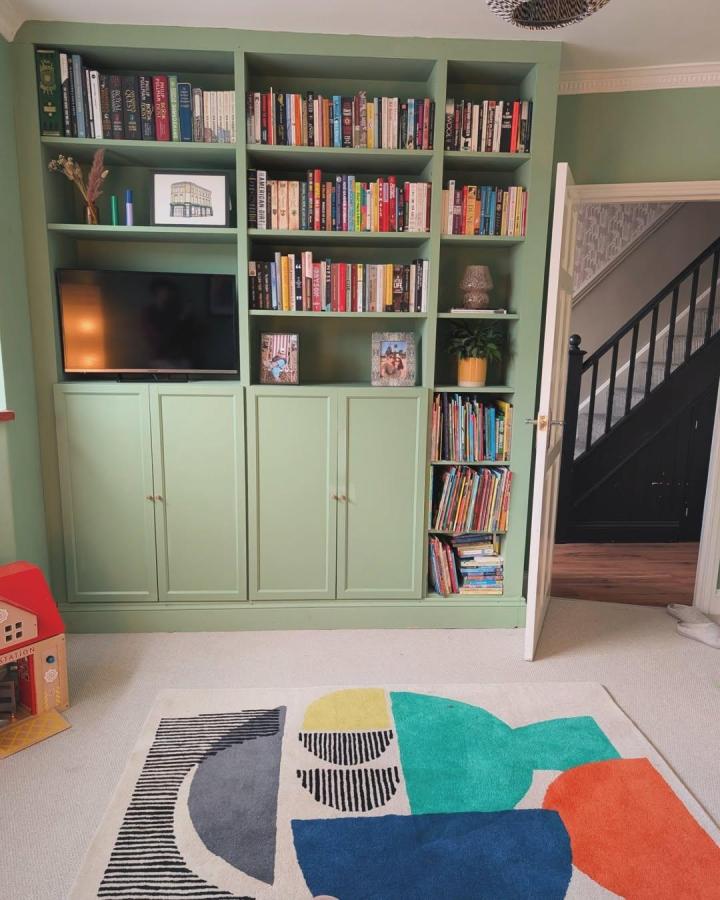 Soft green painted ikea billy library wall hacks with closed lower cabinets and open shelves from @terrifictor showcasing books and decor in a cozy living room setting.
