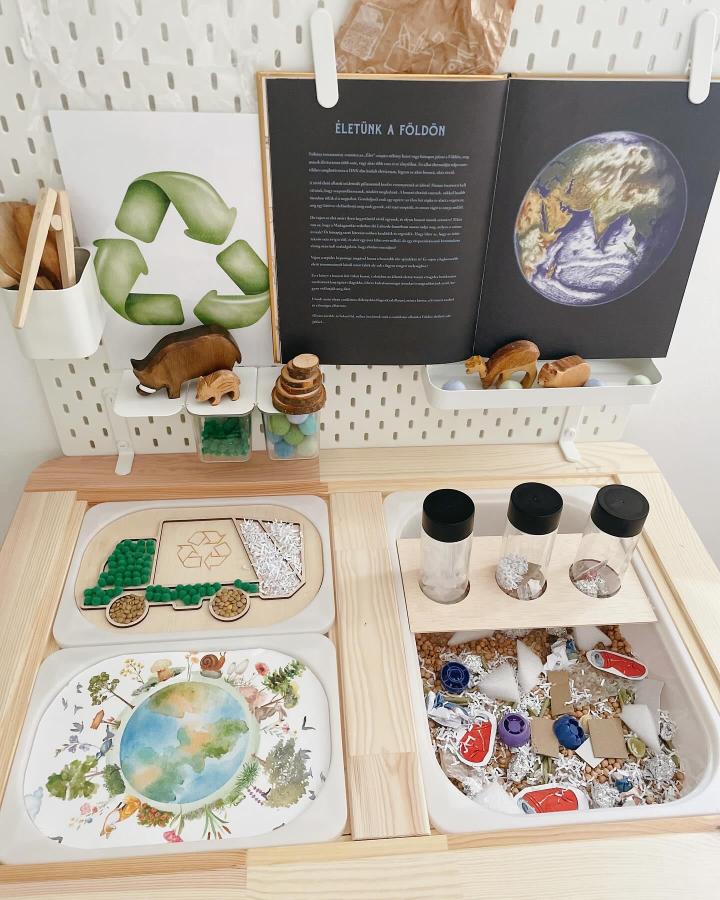 Natural wood Ikea Flisat sensory table with earth tone trays, small glass jars, and nature-themed sorting activities from @panna_asztalkaja. Sustainable learning setup.