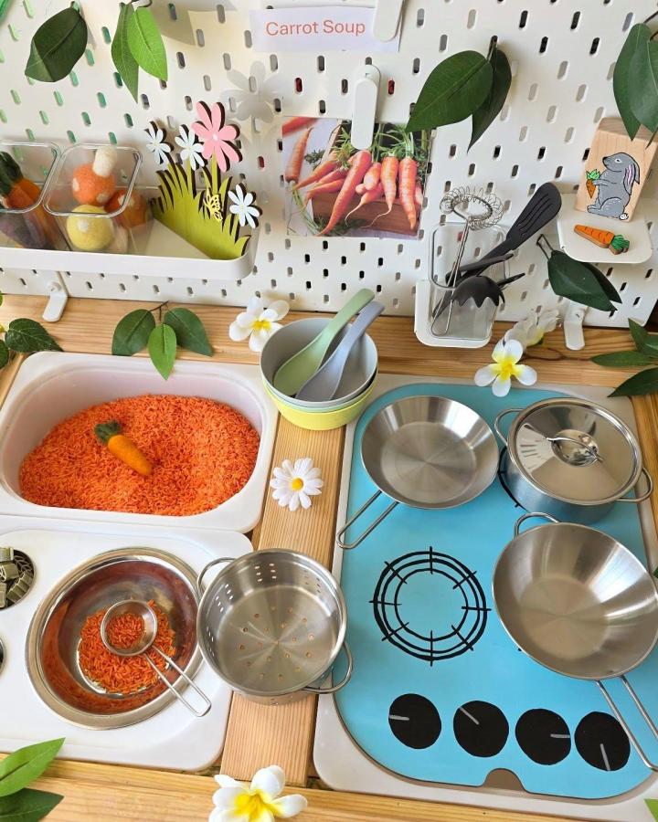 Orange rice sensory play with metal cookware and pegboard accessories from @keepingthelittlesbusy. Ikea flisat sensory table ideas carrot soup theme.