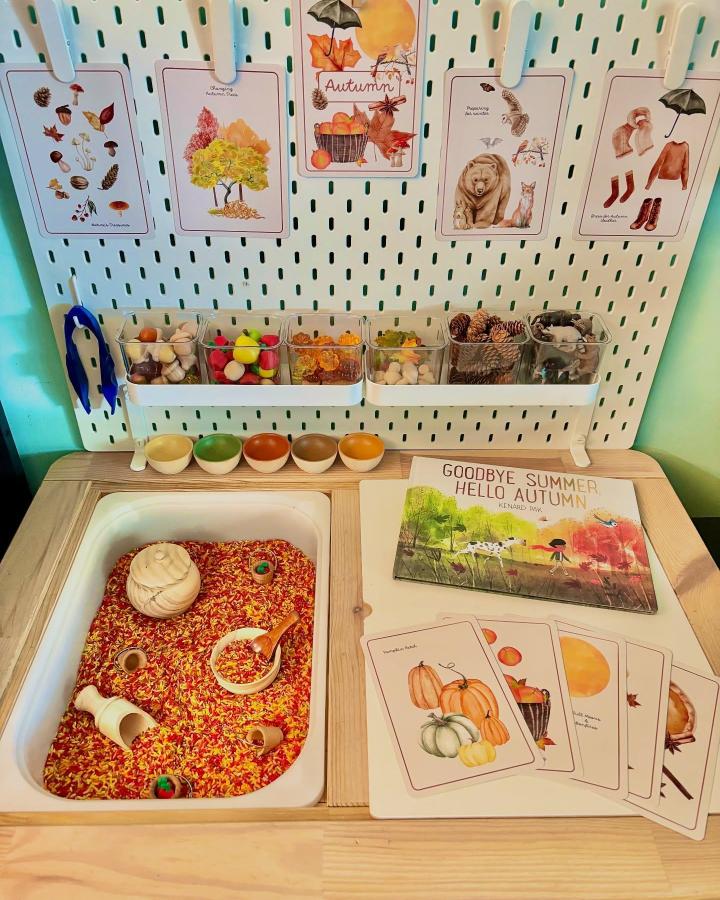 Warm fall colors sensory table with natural elements and educational cards from @playing_the_day_away showing ikea flisat sensory table ideas in use. Bright rice and wooden toys.