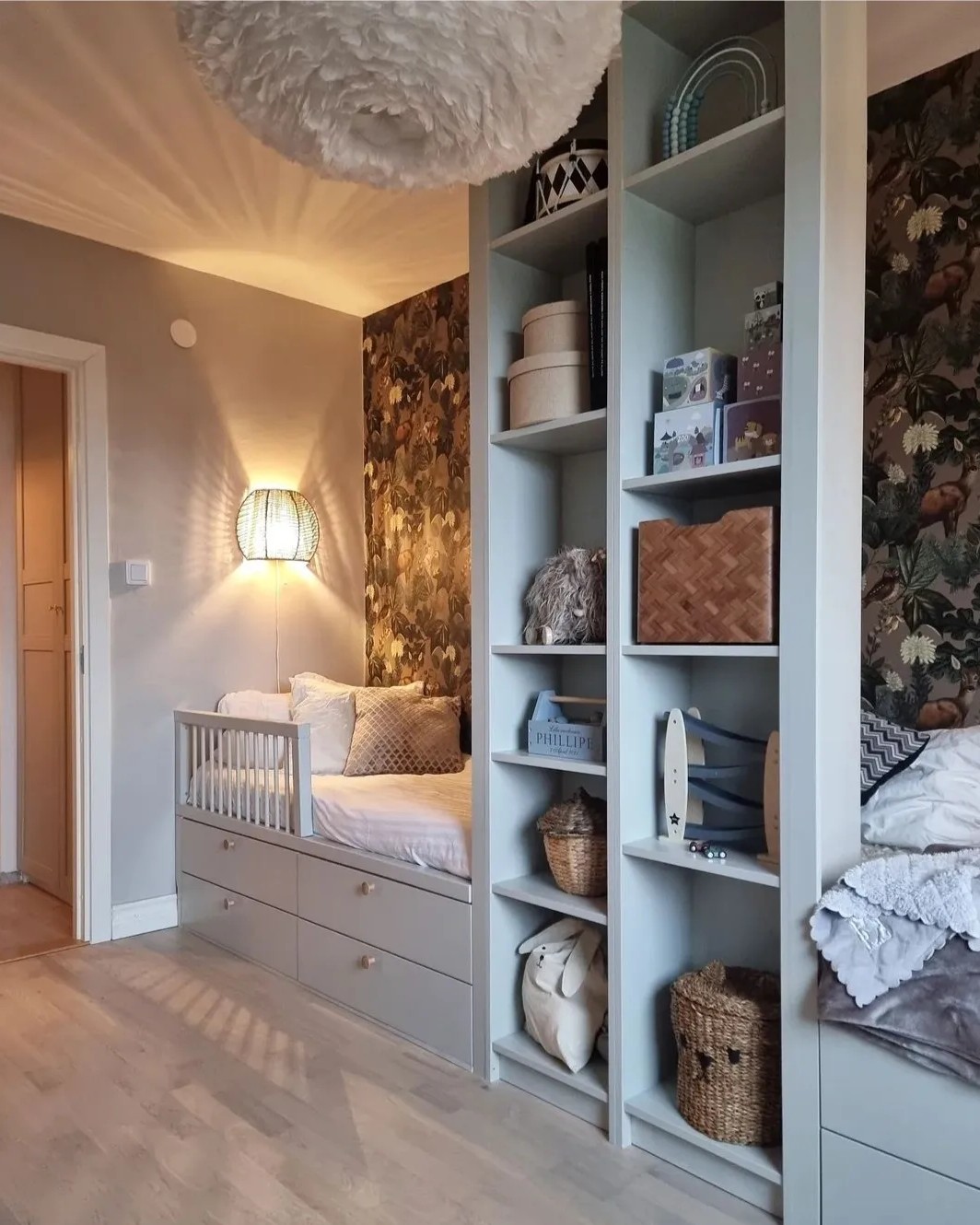 Light gray painted wood built-in daybed and shelving storage unit from @greidesign featuring ikea platsa wardrobe hacks in cozy bedroom corner with floral wallpaper and soft lighting.