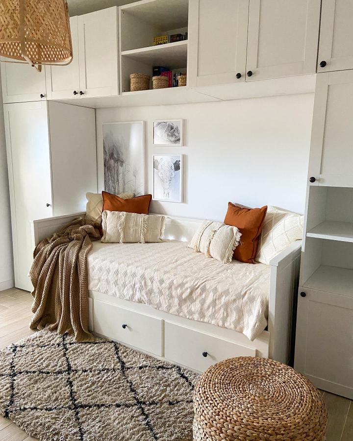 Creamy white Ikea Platsa wardrobe hacks daybed with rust cushions and textured throw blankets by @pichurrynas_mom creating a cozy multi-use space.