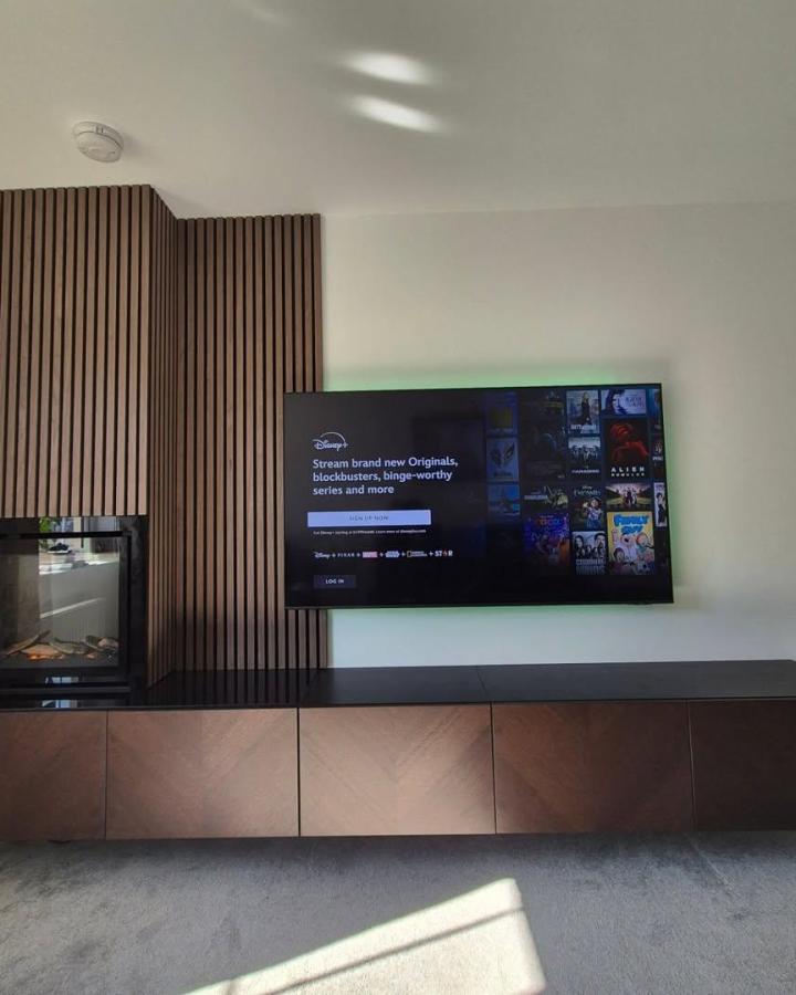 Warm woodgrain floating tv unit with slatted panel wall and angled cabinet fronts by @scot_home showing stylish ikea besta floating tv unit ideas. Modern living room setup.