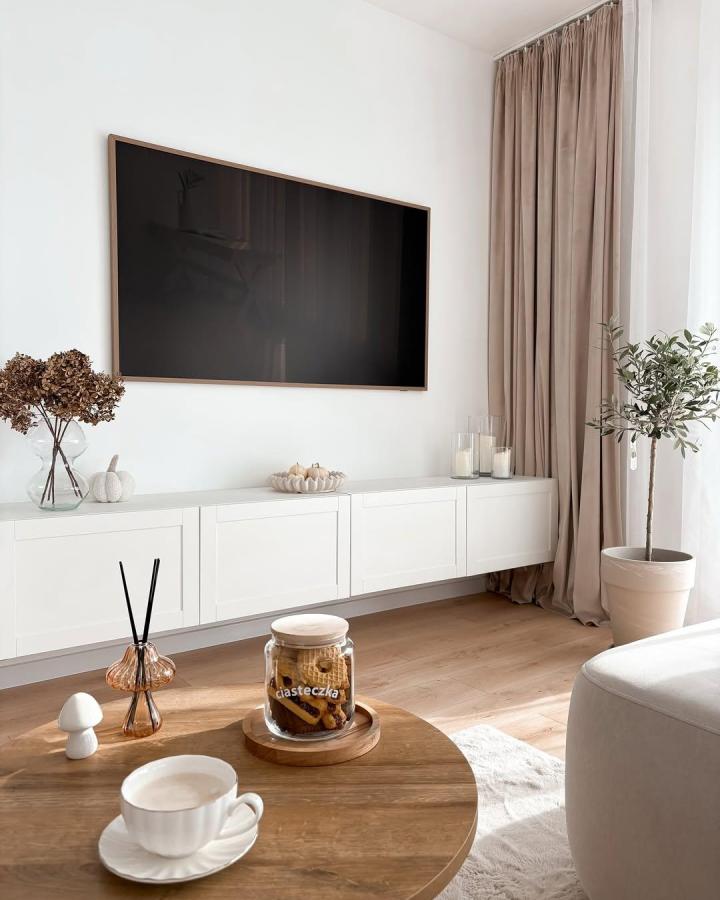 minimalist white ikea besta floating tv unit ideas from @oliwkowe.loove with soft beige curtains and natural wood floor sunlight ambiance