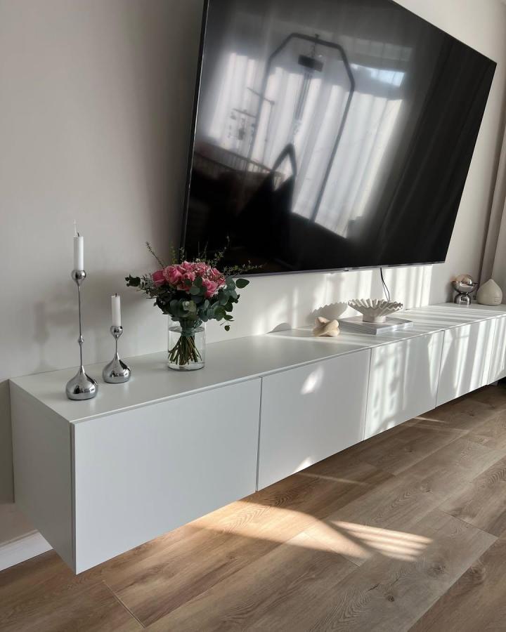 white minimalist floating tv unit ikea besta floating tv unit ideas from @sln.home with clean lines and subtle decor on light wood floor sunlight reflection