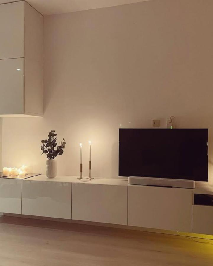 Glossy white minimalist ikea besta floating tv unit ideas from @hackyourinterior with soft candlelight and sleek storage drawers.