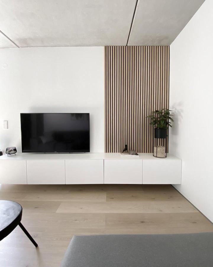 white minimalist ikea besta floating tv unit ideas with slatted oak wood panel backdrop in modern living room from @jane.zuhause clean design and subtle warmth