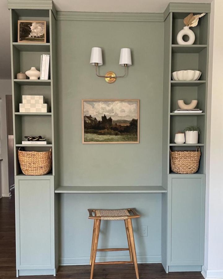 Sage green built-in shelving and desk with woven baskets and ceramics from @raising.tiny.disciples cozy and stylish home nook design