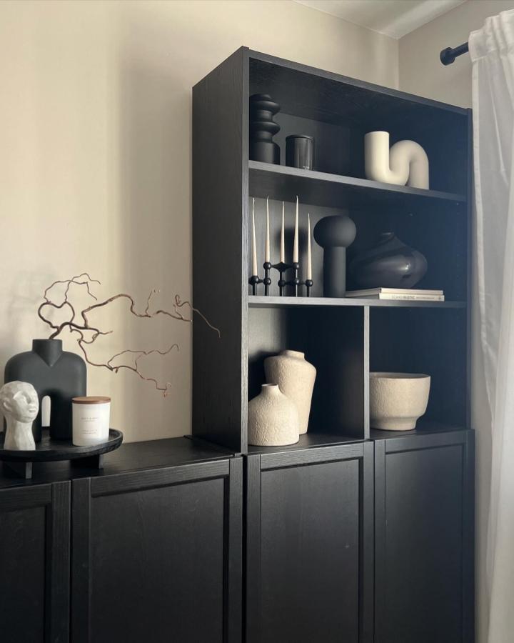 Matte black shelving unit with textured ceramics and sculptural decor from @home_at__no3, modern minimalist style.