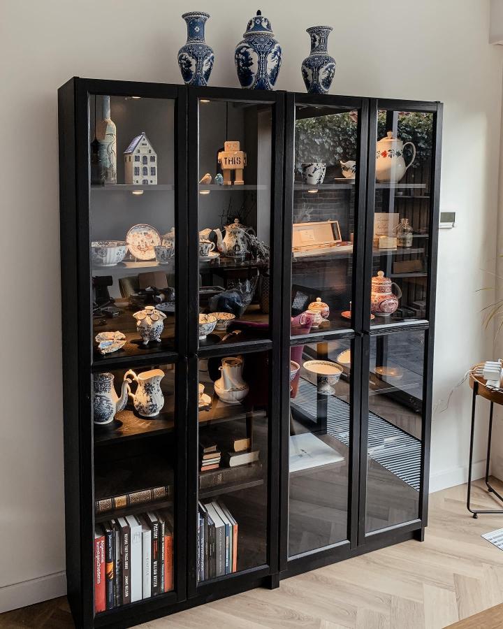 Black framed glass door bookcase with porcelain display and soft lighting by @alexandertromp modern home storage solution