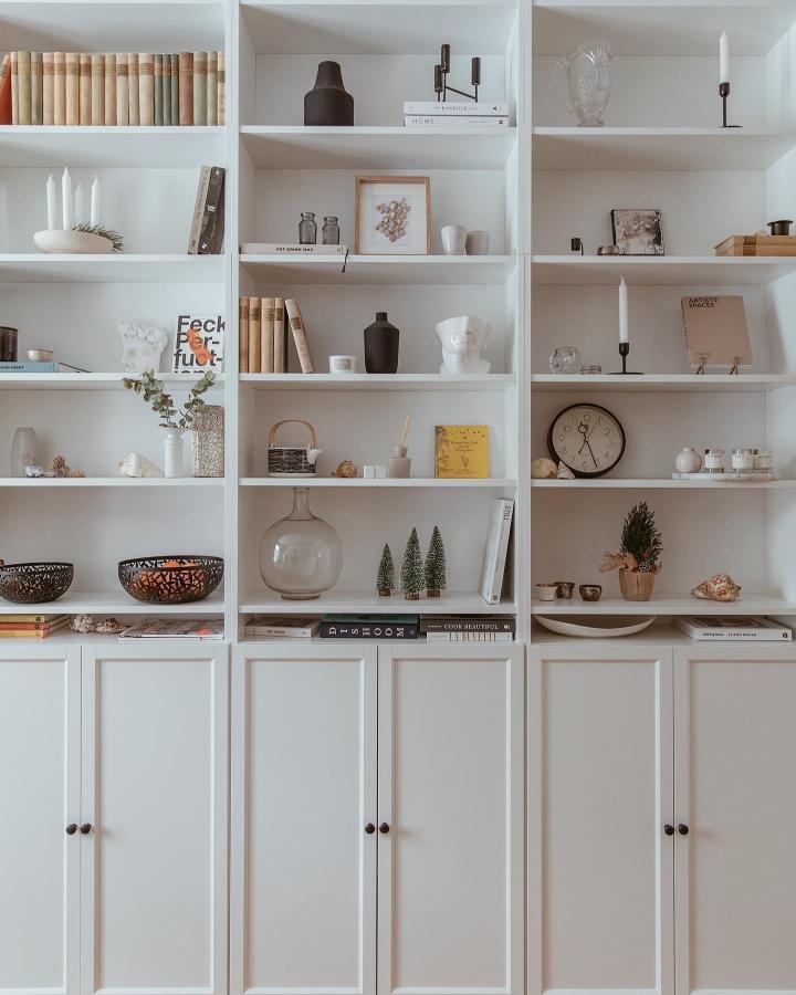 White minimalist Billy Oxberg shelving unit styled with natural decor, books, and art pieces by @kkland