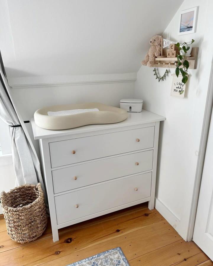 Soft white Ikea Hemnes dresser with beige changing pad and natural wood knobs in a cozy nursery by @hilarymulliganhome. Simple and charming ikea hemnes nursery ideas.