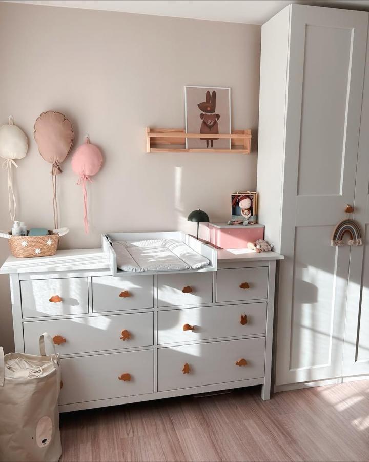 White Ikea Hemnes dresser with wooden animal knobs in a pastel nursery by @barbora_kokes sunlight on floor and walls. ikea hemnes nursery ideas