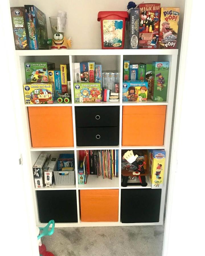 Orange and black fabric drawers on white nine-cube storage unit with kids toys and games by @our_forever_home_interior_ stylish multi-compartment toy organizer.