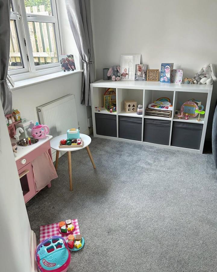 White Kallax shelving unit with dark grey fabric bins and kids toys in a neat playroom by @ourdaviesdiaries. Simple, stylish toy storage solution.
