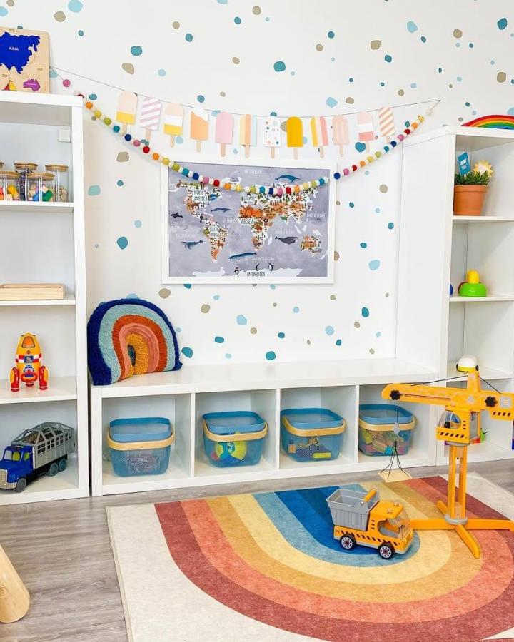 Blue and beige plastic bins stored in white Kallax shelves in a colorful kids room by @playroominspo. Tidy and playful toy organization.