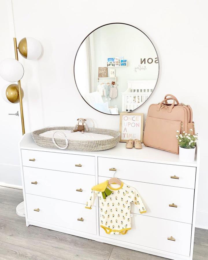 White Ikea Hauga nursery dresser with gold handles and natural woven changing basket styled by @hulovesdecor ikea nursery dresser ideas.