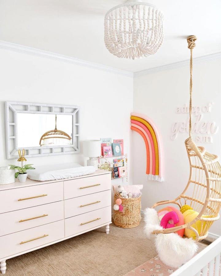 Blush toned wooden dresser with brass handles and turned legs in a cozy nursery by @arinsolange with playful, soft dรฉcor.