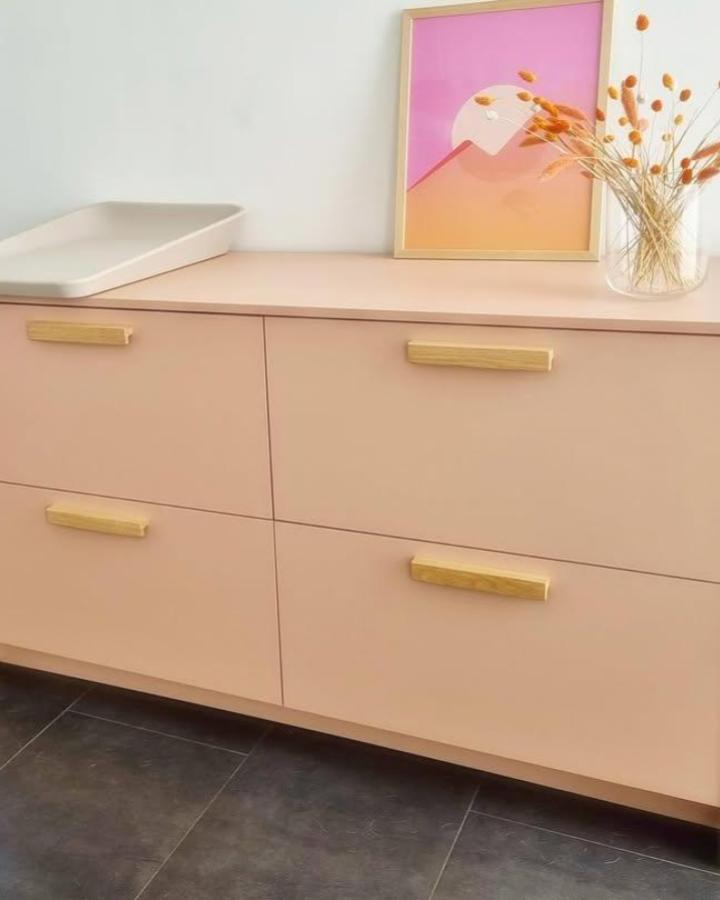 Soft blush pink Ikea Metod dresser with light wood handles in a nursery setting by @frontsbyyta featuring warm natural decor.