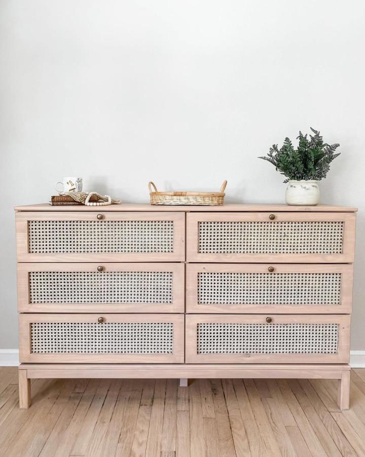 Blush wood dresser with woven cane drawer fronts in a nursery setting by @whiterosefurniture_ with natural and vintage vibes.