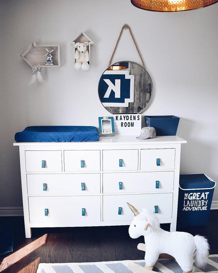 White minimalist nine-drawer dresser with blue leather pulls in nursery by @a.moroccanspinkandgold.dream showcasing ikea nursery dresser ideas.