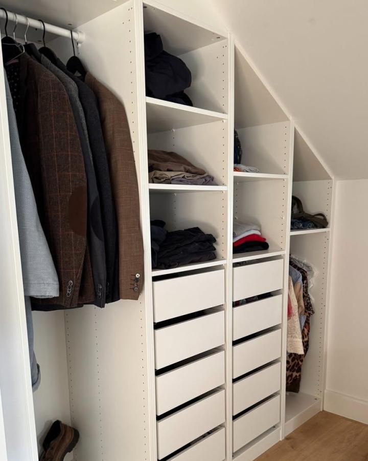 White modular Ikea Pax dressing room ideas by @feelslikehome.dk showing angled ceiling storage with drawers and shelves. Functional attic use.