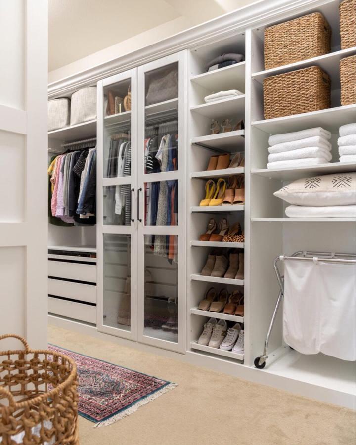 White Ikea Pax wardrobe with glass doors and woven baskets from @crazywonderfulblog. Organized shoe shelves and linen storage in ikea pax dressing room ideas.