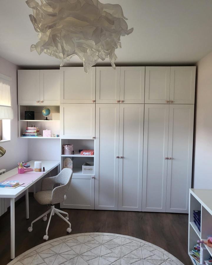 Soft white modular cabinetry with pink knobs in a kid’s room by @afflux.design bright and organized storage space.