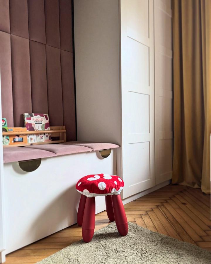 Red polka dot stool and mauve cushioned storage bench with white Platsa frame in kids room by @ola.nowosad.studio, cozy organized play nook.