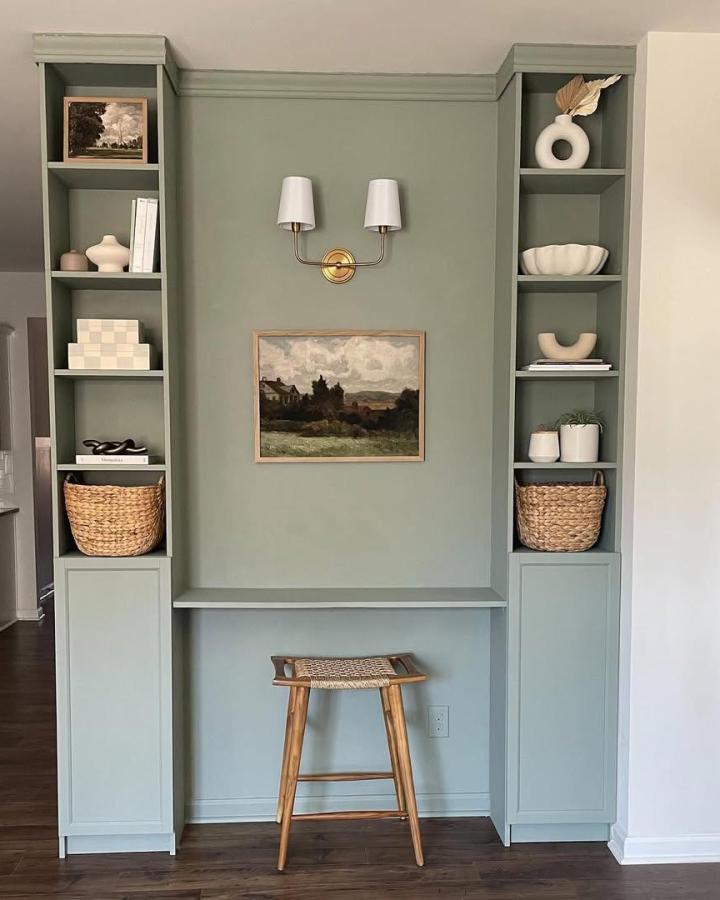 Soft green built in bookshelf and desk from @therenovation_at_no18 showcasing ikea billy bookcase built ins ideas with woven baskets and natural wood stool.