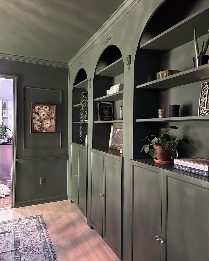 Olive green built in bookcase with arches and glass knobs by @cloudis.home in a cozy living space. Elegant transformation of classic units.