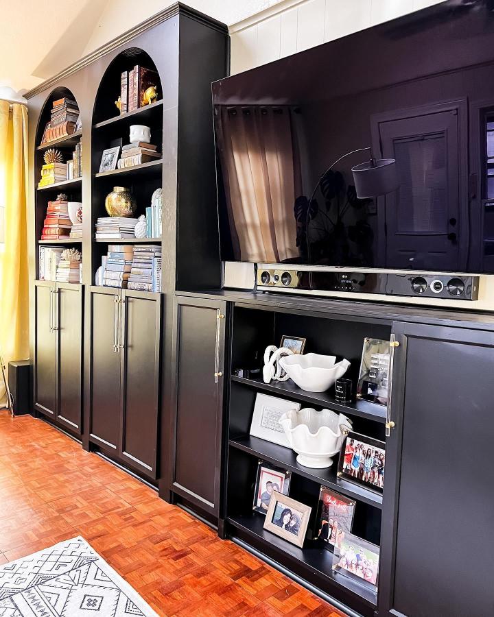 Black matte custom Billy bookcase media wall from @pinchmeimhome with arched upper shelves and sleek cabinetry for a modern living room.